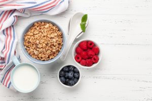 Healthy breakfast with homemade granola and fresh berries on wooden background. Top view with copy space