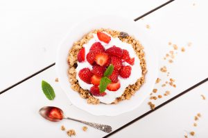 Yogurt with homemade granola or muesli and fresh strawberries for healthy morning breakfast, selective focus, over white. Healthy food background. Top view.