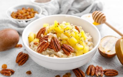 Oatmeal porridge with kiwi fruit, pecan nuts and honey in bowl for breakfast